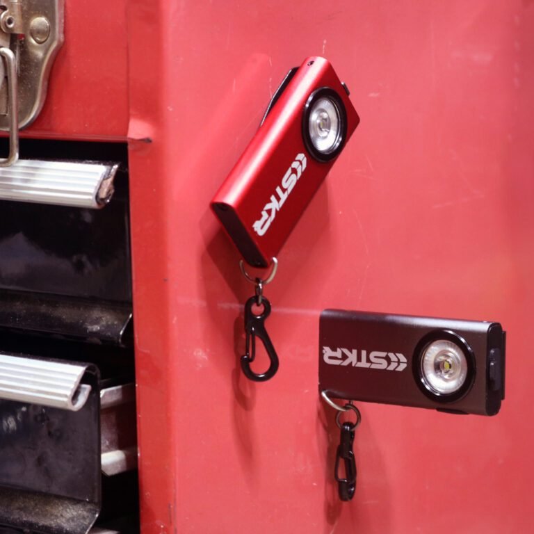 both a red and gray SlimJIMMY magnetically attached to the side of a red toolbox. Each one using a different magnetic attachment point on the keychain light itself.